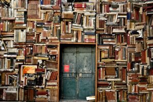 Chaotic overcrowded bookshelves surrounding a door Image via Pikist.com