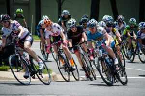 A group of women cyclists in a road race, dressed in colourful cycling gear and leaning over to negotiate a corner.